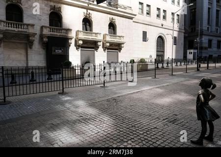 Blick auf das Fearless Girl, eine Bronzeskulptur auf der Broad Street gegenüber dem New York Stock Exchange Building in Manhattan, New York City. Stockfoto