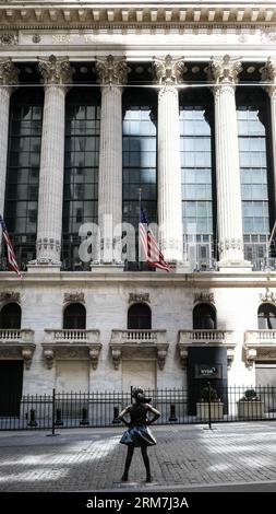 Blick auf das Fearless Girl, eine Bronzeskulptur auf der Broad Street gegenüber dem New York Stock Exchange Building in Manhattan, New York City. Stockfoto