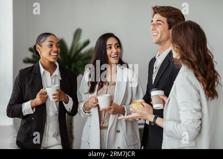 Gruppe multiethnischer Kollegen, die mit einer Tasse Kaffee stehen und während der Kaffeepause im Büro sprechen Stockfoto