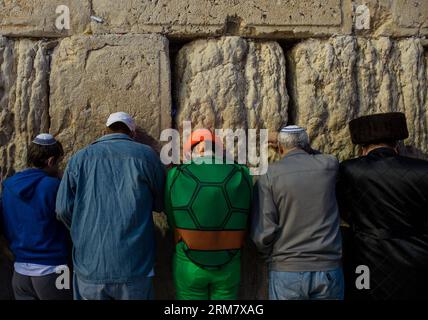 JERUSALEM, 17. März 2014 – Ein jüdischer Mann (C), der als Karikaturfigur Turtles Forever verkleidet ist, betet am 17. März 2014 an der Westmauer in der Altstadt von Jerusalem während der Purim-Feiertage. Purim, dieses Jahr von Sonnenuntergang, 15. März bis Einbruch der Nacht, 16. März und einen Tag später in Jerusalem gefeiert, ist einer der freudigsten und lustigsten Feiertage im jüdischen Kalender. Es erinnert an eine Zeit, in der das jüdische Volk in Persien vor der Vernichtung gerettet wurde. (Xinhua/Li Rui) MIDEAST-JERUSALEM-PURIM-CELEBRATION PUBLICATIONxNOTxINxCHN Jerusalem 17. März 2014 ein jüdischer Mann C verkleidet als der Cartoon Stockfoto