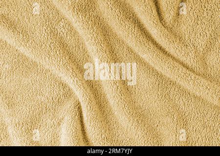 Frottee, gelber Handtuchhintergrund. Zerknittertes und zerknittertes, weiches, flauschiges Textil-Bad- oder Strandhandtuchmaterial. Draufsicht, Nahaufnahme. Stockfoto