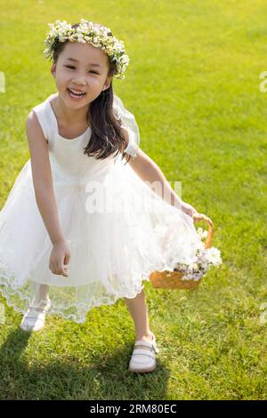 Niedliches Blumenmädchen, das auf dem Gras spielt Stockfoto