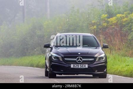 Whittlebury, Northants, UK - 26. August 2023: 2014 purpurroter Mercedes Benz CLA 45 AMG-Wagen, der an einem feuchten und nebligen Morgen auf einer englischen Landstraße fährt. Stockfoto