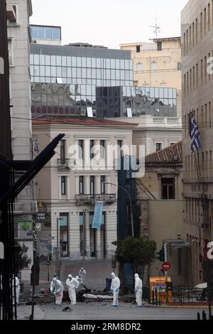 ATHEN, Polizei-Bombenbeseitigungsexperten suchen nach Beweisen in der Nähe von Überresten eines Autos nach einer Autobombenexplosion im Zentrum von Athen, Griechenland, am 10. April 2014. Eine Autobombe explodierte am frühen Donnerstag vor der griechischen Zentralbank im Zentrum von Athen und verursachte Schäden an Büros, Geschäften und Autos in der Nähe. Es wurden keine Verletzungen gemeldet. Der Vorfall ereignete sich zu einer Zeit, als Griechenland am Donnerstag zum ersten Mal seit Beginn der Krise im Jahr 2010 seine Rückkehr an die internationalen Anleihemärkte machen sollte, indem es den Anlegern fünfjährige Anleihen anbot. (Xinhua/Marios Lolos) (lyx) GRIECHENLAND-ATHEN-CAR BOMB-BLAST Stockfoto