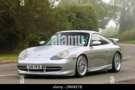 Whittlebury, Northants, UK - 26. August 2023: 1998 silberner Porsche 911 Carrera-Wagen, der an einem feuchten und nebligen Morgen auf einer englischen Landstraße fährt. Stockfoto