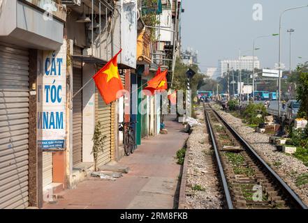 Vietnamesische goldene rote Flaggen fliegen auf Stangen vor verschlossenen Geschäften entlang der Nord-Süd-Hauptbahnstrecke in der Giai Phong Road, auf der Autobahn 1, Stockfoto