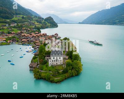 Blick aus der Vogelperspektive auf das Dorf Iseltwald am Südufer des Brienzersees, einem der atemberaubendsten türkisfarbenen Seen der Schweiz. Stockfoto