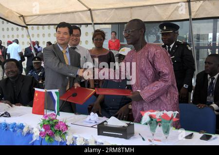 BO, 25. April 2014 - Zhao Yanbo (L, Front), der chinesische Botschafter in Sierra Leone, gibt Paul Kamara, dem Sportminister Sierra Leones, die Hand, nachdem sie die Übergabedokumente in Bo, der zweitgrößten Stadt Sierra Leones, am 25. April 2014 unterzeichnet haben. Das Bo Stadium, ein viertausend Sitzplätze umfassendes Stadion, das von der Xinjiang Beixin Construction and Engineering Group Company Limited gebaut und von der chinesischen Regierung zu fast zehn Millionen US-Dollar unterstützt wurde, wurde von Zhao Yanbo, dem chinesischen Botschafter in Sierra Leone, übergeben. an das Ministerium von Sierra Leone in Bo am Freitag. (Xinhu Stockfoto