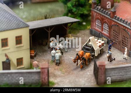 Miniatur-Diorama im Miniatur Wunderland in Hamburg, zeigt eine historische Szene mit Pferdewagen und Menschen außerhalb einer Fabrik Stockfoto