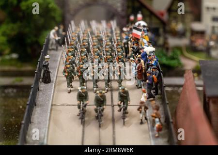 Miniatur-Diorama im Miniatur Wunderland in Hamburg, zeigt Soldaten, die über eine Brücke durch eine Gruppe von Zivilisten ziehen Stockfoto