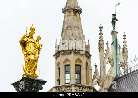 Marienstatue auf dem Marienplatz beim Rathaus, München, Deutschland. Dieser Ort ist das Wahrzeichen Münchens. Goldene Skulptur auf der Mariensaule-Säule Stockfoto