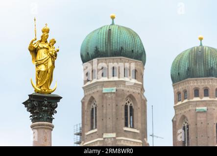 Marienstatue auf Himmelshintergrund am Marienplatz, München. Dieser Ort ist das Wahrzeichen Münchens. Blick auf die goldene Skulptur auf dem Mariensaule Stockfoto