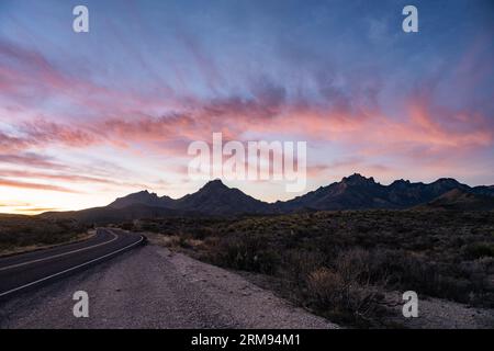 Hellrosa Wolken hängen über den Chisos Mountains bei Sunrise im Big Bend National Park Stockfoto