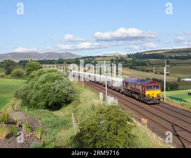 DB Cargo Lokomotive der Baureihe 66 in EWS-LackierpassingDocker (nördlich von Oxenhome auf der Westküstenhauptstrecke) mit einem Güterzug mit Kalk Stockfoto