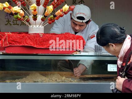 (140513) -- PEKING, 13. Mai 2014 (Xinhua) -- Foto aufgenommen am 28. November 2013 zeigt einen Arbeiter, der Erdnussbonbons für einen Kunden in Fuzhou, der Hauptstadt der südöstlichen chinesischen Provinz Fujian, servierte. Eine der beliebtesten Arten weltweit, chinesische Küche ist berühmt für ihren Geschmack und ihre Vielfalt, mit einer beispiellosen Auswahl an Zutaten, Techniken, Gerichten und Essstilen. Die Geschichte der chinesischen Küche reicht seit Tausenden von Jahren zurück und hat sich von Periode zu Periode und in jeder Region je nach Klima, Tradition und lokalen Präferenzen verändert. Die Chinesen sind stolz darauf, eine große Auswahl an Lebensmitteln zu essen Stockfoto