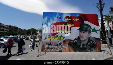 DAMASCUS, May 13, 2014 - People walk past an election campaign billboard of incumbent President Bashar al-Assad in Damascus, capital of Syria, May 13, 2014. Posters and banners of Syria s three presidential candidates decorate the main streets in Damascus, with incumbent President Bashar al-Assad predictably receiving the lion share of the publicity, as campaigning for the elections begin on May 12. Syria s supreme constitutional court accepted the candidacy of three contenders, including namely Maher Abdul-Hafiz Hajjar, Hassan Abdullah al-Nouri and Bashar al-Assad, for the June 3 presidential Stock Photo