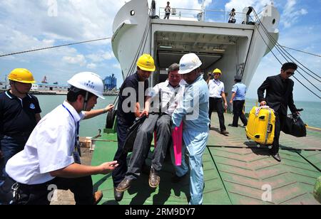 (140520) -- HAIKOU, May 20, 2014 (Xinhua) -- Medical workers carry an injured Chinese worker as they disembark from the passenger vessel Tongguling at the Xiuying Port in Haikou, capital of south China s Hainan Province, May 20, 2014. Violence-stricken Chinese workers in Vietnam arrived at the port in Haikou on Tuesday. The Chinese government sent four vessels on Sunday to evacuate riot-stricken Chinese workers in Vietnam where severe violence targeting foreign companies since May 13 has left two Chinese nationals dead and more than 100 others injured. (Xinhua/Guo Cheng) (lfj) CHINA-HAINAN-HAI Stock Photo