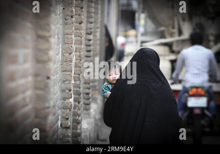 (140520) -- TEHRAN, May 20, 2014 (Xinhua) -- A woman wearing chador carries her child on an alley in Tehran, capital of Iran, May 19, 2014. Chador is a kind of formal Hijab for many women in Iran in public places. Hijab, a coverage of hair and body for women, has been obligated in public after the Islamic revolution in Iran in 1979. (Xinhua/Ahmad Halabisaz)(zhf) IRAN-TEHRAN-WOMEN-HIJAB PUBLICATIONxNOTxINxCHN   TEHRAN May 20 2014 XINHUA a Woman Wearing chador carries her Child ON to Alley in TEHRAN Capital of Iran May 19 2014 chador IS a Child of formal Hijab for MANY Women in Iran in Public Pl Stock Photo