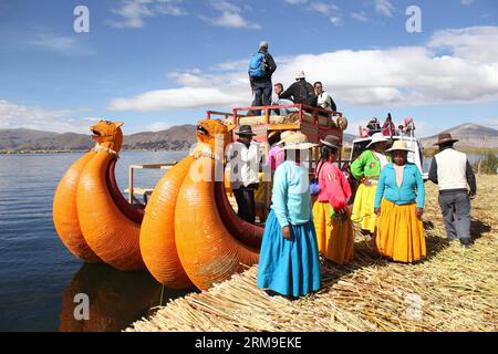 (140520) -- PUNO, May 20, 2014 (Xinhua) -- Women stand in front of a boat on Los Uros floating island at Titicaca Lake, in Puno region, Peru, May 13, 2014. The Titicaca Lake and its floating islands in Peru s Puno region have not only natural attractions but also unique culture because of the Quechua people from Juliaca living there. The Titicaca Lake is located in Collao Plateau, with the islands of Luna, Taquile, Amantani, Uros and Suriqui in it. (Xinhua/Luis Camacho)(zhf) PERU-PUNO-TITICACA LAKE-FLOATING ISLAND PUBLICATIONxNOTxINxCHN   Puno May 20 2014 XINHUA Women stand in Front of a Boat Stock Photo