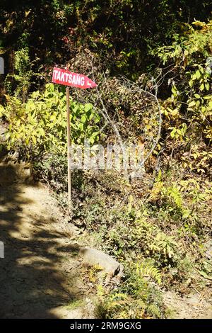 Rot bemalte Schilder zeigen den Weg nach Taktsang, Bhutans berühmtem Tigernestkloster in der Nähe von Paro, Bhutan. Der 3-Meilen-Trail klettert 1.699 Meter hoch Stockfoto