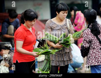 Die Verbraucher wählen auf einem Markt in der Gemeinde Sizhou in Shangrao, Ostchinesische Provinz Jiangxi, Blätter aus, die für die Herstellung von Zongzi verwendet werden, einem pyramidenförmigen Knödel aus glutinösem Reis, der in Bambus oder Schilfblätter gewickelt ist. Dieser Markt ist am 25. Mai 2014 erhältlich. Chinesen haben die Tradition, Zongzi zu essen, um das Dragon Boat Festival zu begrüßen, das dieses Jahr am 2. Juni stattfindet. (Xinhua/Zhuo Zhongwei) (ry) CHINA-JIANGXI-DRAGON BOAT FESTIVAL-PREPARATES (CN) PUBLICATIONxNOTxINxCHN Consumer Select Leaves used to make Zongzi a Pyramid Shaped Dumpling made of glutinous Rice wrapped in Bamboo or Reed Leaves at at a Market in Sizhou Township of Shangrao Stockfoto