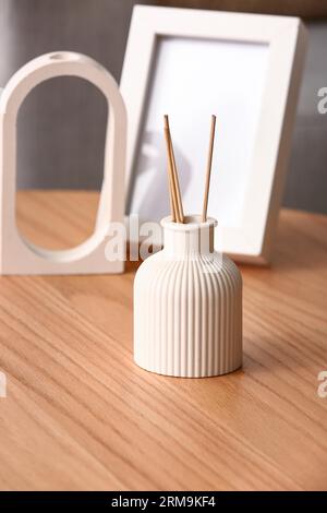 Flasche Reed-Diffusor und leerer Rahmen auf Tisch im Raum, Nahaufnahme Stockfoto