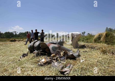 (140527) -- SRINAGAR, 27. Mai 2014 (Xinhua) -- die Menschen betrachten die Trümmer eines IAF-Kampfflugzeugs im Dorf Marhama-Bijbehara, etwa 50 km südlich von Srinagar, der Sommerhauptstadt des von Indien kontrollierten Kaschmirs, am 27. Mai 2014. Der Ministerpräsident des von Indien kontrollierten Kaschmir Omar Abdullah äußerte am Dienstag sein Beileid über die Ermordung eines IAF-Piloten bei einem MiG-21-Absturz. (Xinhua/Javed dar) KASHMIR-SRINAGAR-INDIAN AIR FORCE-CRASH PUBLICATIONxNOTxINxCHN Srinagar Mai 27 2014 XINHUA Prominente Schauen Sie SICH die Trümmer von to IAF Fighter Jet IN Village etwa 50 km südlich von Srinagar City, dem Summer Capi Stockfoto