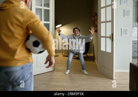 Fröhliches Seniorenpaar, das Fußball spielt, selektiver Fokus auf den Ball in der Hand des Menschen Stockfoto