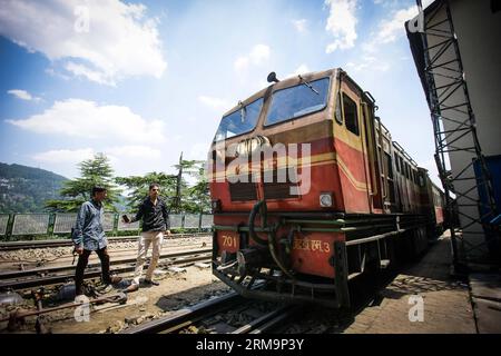 HIMACHAL PRADESH, May 28, 2013 (Xinhua) -- Passengers look at a train on the Kalka-Shimla Railway in Shimla, north India s Himachal Pradesh, May 28, 2014. The Kalka-Shimla Railway is a 762?mm narrow gauge railway in North-West India s Himachal Pradesh travelling along a mostly mountainous route from Kalka to Shimla. It is known for dramatic views of the hills and surrounding villages. The 96-km long railway was built since 1898 to provide a service to the highland town of Shimla. Three still fully operational railways, the Darjeeling Himalayan Railway in India s West Bengal, the Nilgiri Mounta Stock Photo