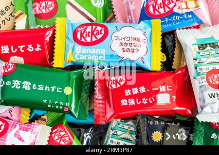 Bunte Auswahl verschiedener Gefälligkeiten japanischer Mini-zwei-Bar-Kit-Kats in einem kleinen Stapel, der von Rand zu Rand des Rahmens verläuft. Stockfoto