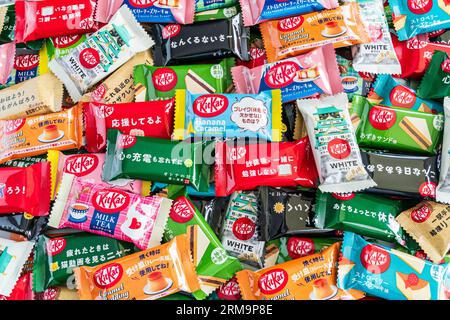 Bunte Auswahl verschiedener Gefälligkeiten japanischer Mini-zwei-Bar-Kit-Kats in einem kleinen Stapel, der von Rand zu Rand des Rahmens verläuft. Stockfoto