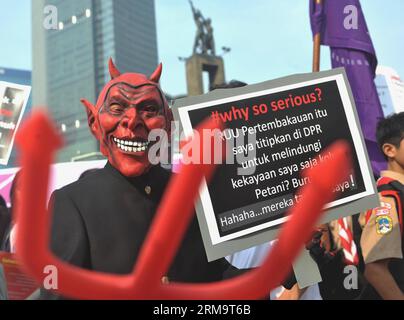 Ein Mann mit einer Maske hält ein Plakat während einer Gedenkfeier zum Welttag des Tabaks, markiert am 31. Mai, in Jakarta, Indonesien, 1. Juni 2014. Indonesien ist zwar aktiv an der Ausarbeitung des Rahmenübereinkommens der Weltgesundheitsorganisation zur Eindämmung des Tabakkonsums beteiligt, aber nach wie vor das einzige Land, das den Rahmen unter den asiatisch-pazifischen Ländern nicht unterzeichnet und ratifiziert hat. (Xinhua/Agung Kuncahya B.) INDONESIEN-JAKARTA-WORLD NO-TOBACCO DAY PUBLICATIONxNOTxINxCHN ein Mann mit Maske hält ein Plakat während einer Gedenkfeier zum Welttag des Tabakverbots AM 31. Mai in Jakarta, Indonesien, 1. Juni 2014 Stockfoto