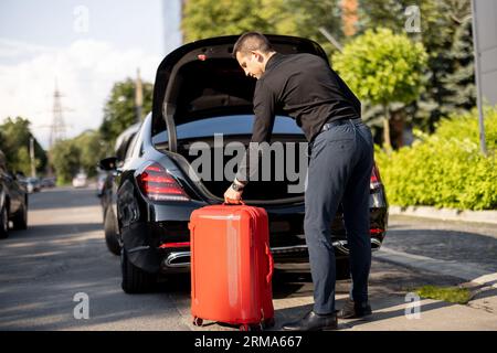 Chauffeur packt einen Koffer in ein Luxusauto Stockfoto