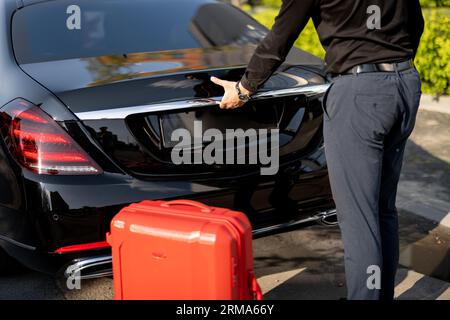 Chauffeur packt einen Koffer in ein Luxusauto Stockfoto