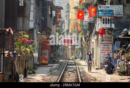 Eine vietnamesische Frau, die eine Gesichtsmaske trägt, geht entlang der Nord-Süd-Eisenbahnlinie, die Wohngebiete vor der Kham Thien Street in Hanoi, V durchschneidet Stockfoto