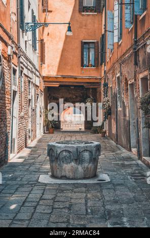 Enge Fußgängerzone mit Kopfsteinpflaster in Venedig, Italien. Alte, verschlissene mittelalterliche Gebäude. Stockfoto