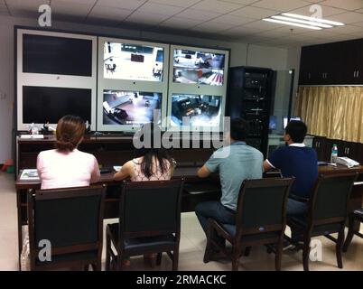 (140702) -- YICHUN, July 2, 2014 (Xinhua) -- Teachers supervise an exclusive college entrance exam taken by Liu Yanbing and Yi Zhengyong on real-time monitoring screen in Yichun, east China s Jiangxi Province, July 2, 2014. Liu Yanbing and Yi Zhengyong, both from No.3 Middle School in Yichun, were seriously injured during a fight against an assailant who was stabbing passengers on a bus on May 31. They were unable to take the national college entrance exam, on June 7 and 8 as they were still recovering from their injuries. It is the first time Jiangxi s educational authority has organized a se Stock Photo