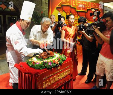 (140702) -- PEKING, 2. Juli 2014 (Xinhua) -- Yang Dengyan (2. L), der erste Präsident der Quanjude Group, schneidet Quanjudes 196-millionste Röstente während einer Zeremonie zum 150-jährigen Bestehen des Quanjude Beijing Roast Duck Restaurant in seiner Qianmen Niederlassung in Peking, Hauptstadt von China, am 2. Juli 2014. Quanjude, das seit seiner Gründung im Jahr 1864 in seiner Qianmen-Niederlassung in Peking für sein langjähriges kulinarisches Erbe bekannt ist, erhielt sein 150-jähriges Bestehen und eine Zeremonie zur Feier seiner 196-Jahrtausendgebratenen Ente fand hier statt. (Xinhua/Zhang Yan) (lfj) CHINA-BEIJING-QUANJUDE-150th Stockfoto