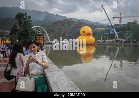 (140703) -- GUIYANG, July 3, 2014 (Xinhua) -- A resident poses for photos with a giant yellow rubber duck floating on Nanming River in Guiyang, capital of southwest China s Guizhou Province, July 3, 2014. The 18-meter-tall rubber duck, brainchild of Dutch artist Florentijn Hofman, will berth in Guiyang from July 4 to August 24. (Xinhua/Ou Dongqu) (lfj) CHINA-GUIZHOU-GUIYANG-GIANT YELLOW RUBBER DUCK (CN) PUBLICATIONxNOTxINxCHN   Guiyang July 3 2014 XINHUA a Resident Poses for Photos With a Giant Yellow Rubber Duck Floating ON Nanming River in Guiyang Capital of Southwest China S Guizhou Provinc Stockfoto