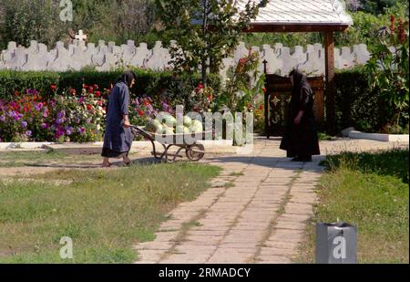 Kloster Vladimiresti, Kreis Galati, Rumänien, 1999. Ältere Nonne mit einer schweren, mit Wassermelonen gefüllten Schubkarre. Stockfoto