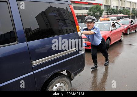 (140704) -- TAIYUAN, 4. Juli 2014 (Xinhua) -- Ein Polizist hilft, ein Auto zu schieben, das in Taiyuan, der Hauptstadt der nordchinesischen Provinz Shanxi, am 4. Juli 2014 festgefahren ist. Am Freitag überfluteten Regenfälle die Straßen und verursachten Verkehrsunterbrechungen. (Xinhua/Zhan Yan) (mp) CHINA-SHANXI-TAIYUAN-REGENFÄLLE (CN) PUBLICATIONxNOTxINxCHN Taiyuan 4. Juli 2014 XINHUA ein Polizist hilft, ein Auto zu schieben Thatcher ist in der Hauptstadt Taiyuans der Provinz S Shanxi AM 4. Juli 2014 festgefahren Stockfoto