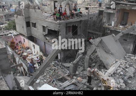 (140710) - Gaza, 10. Juli 2014 (Xinhua) - palästinensische Rettungskräfte und Bewohner inspizieren ein Gebäude, das am 10. Juli 2014 von einem israelischen Luftangriff getroffen wurde, bei dem acht Menschen in der Stadt Khan Yunis im südlichen Gazastreifen ums Leben kamen. Das gesundheitsministerium sagte in einer Presseerklärung, dass 81 Palästinenser bei den israelischen Luftangriffen auf den Gazastreifen getötet und 567 verwundet wurden, wobei 70 Prozent der Opfer Zivilisten seien, die meisten davon Frauen und Kinder. Während die israelische Luftwaffe über Nacht mehr als 300 Hamas-Ziele im Gazastreifen traf, als Reaktion auf Raketenbeschüsse aus dem belagerten palästinensischen Gebiet, eine Armee Stockfoto