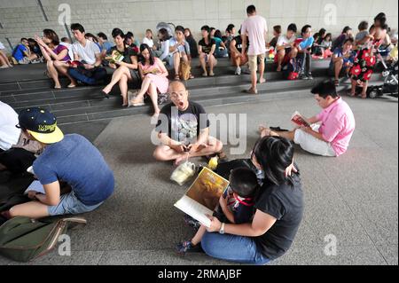 (140713) -- SINGAPUR, 13. Juli 2014 (Xinhua) -- Menschen besuchen eine Lesesitzung vor dem Gebäude der Nationalbibliothek in Singapur, 13. Juli 2014. Ein Minister der Regierung hat gesagt, dass sich das National Library Board of Singapore bei seiner jüngsten Entscheidung, drei Titel von Kindern über alternative Familien zurückzuziehen, von Gemeinschaftsnormen leiten ließ, berichteten lokale Medien am Samstag. (Xinhua/Then Chih Wey) SINGAPORE-CHILDREN S BOOK-KONTROVERSE PUBLICATIONxNOTxINxCHN Singapur 13. Juli 2014 XINHUA-Prominente nehmen an einer Lesesitzung vor dem National Library Building in Singapur Teil 13. Juli 2014 a Governn Stockfoto