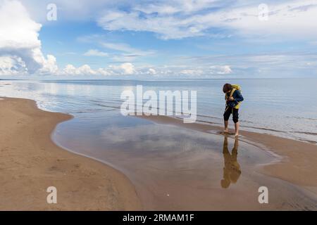 Touristen-Wanderer, Teenager mit Rucksack, der den wunderschönen Sandstrand von Alajoe am Peipus-See an einem klaren sonnigen Tag in Estland erkundet, Stockfoto