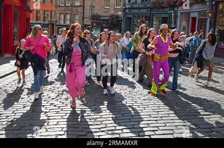 Grassmarket, Edinburgh, Schottland, Großbritannien. 27. August 2023. Die stille Disco unter der Leitung von David für Guru Dudu führt durch Grassmarket und in die Victoria Street im Stadtzentrum. Diese häufigen Veranstaltungen wurden von einigen Einheimischen negativ kommentiert, da die Teilnehmer oft die Lieder auf ihren Kopfhörern laut auf ihren Stimmen singen, andere Passanten sich über die Szene amüsieren. Quelle: Archwhite/Alamy Live News. Stockfoto