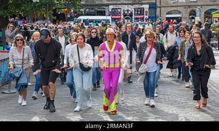 Grassmarket, Edinburgh, Schottland, Großbritannien. 27. August 2023. Die stille Disco unter der Leitung von David für Guru Dudu führt durch Grassmarket und in die Victoria Street im Stadtzentrum. Diese häufigen Veranstaltungen wurden von einigen Einheimischen negativ kommentiert, da die Teilnehmer oft die Lieder auf ihren Kopfhörern laut auf ihren Stimmen singen, andere Passanten sich über die Szene amüsieren. Quelle: Archwhite/Alamy Live News. Stockfoto