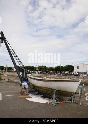 Mann, der an der Bootswartung arbeitet, Hafen von Noirmoutier en i'Ile bei Ebbe. Noirmoutier, Vendee, Frankreich Stockfoto