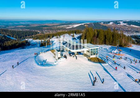 Skipiste, Sessellift, Skifahrer und Snowboarder im Skigebiet Bialka Tatrzanska in Polen auf dem Berg Jankulakowski Wierch im Winter. Luftaufnahme in der Sonne Stockfoto