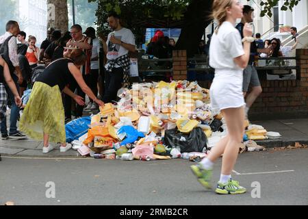 London, Großbritannien. 27. August 2023. Auf der Bordsteinkante werden entsorgte Lebensmittelbehälter gestapelt. Darsteller während der Kinderparade am Familientag beim Notting Hill Carnival in London. Der Notting Hill Carnival, Europas größtes Straßenfest, das die karibische Kultur feiert, wird täglich mehr als eine Million Besucher anziehen. Quelle: Waldemar Sikora / Alamy Live News Stockfoto