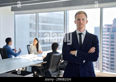 Selbstbewusster Teammanager eines jungen Geschäftsmannes, der im Büro steht. Hochformat Stockfoto